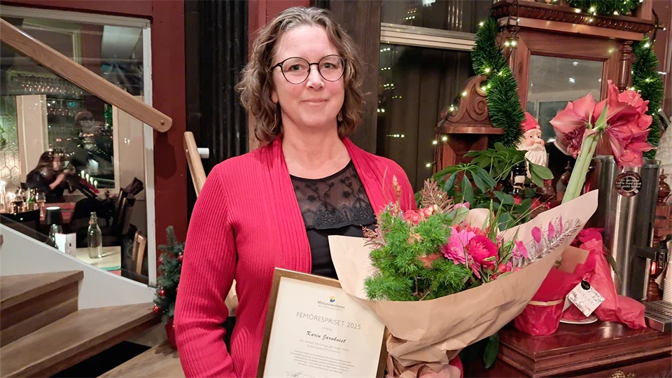 Kvinna i röd kavaj med diplom och blombukett i famnen