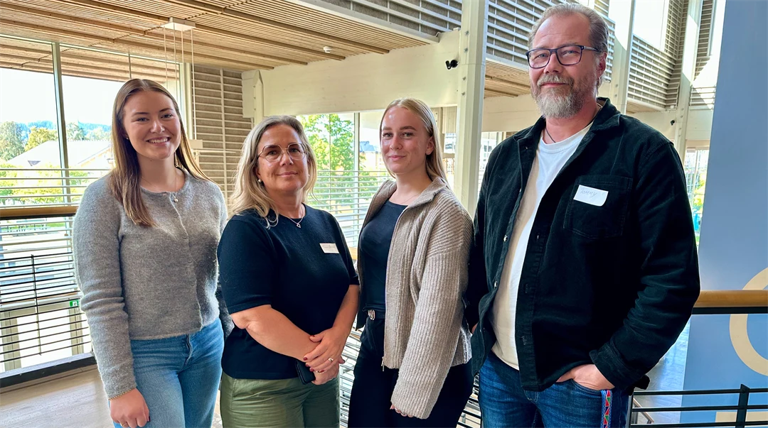 Tre kvinnor och en man ler mot kameran