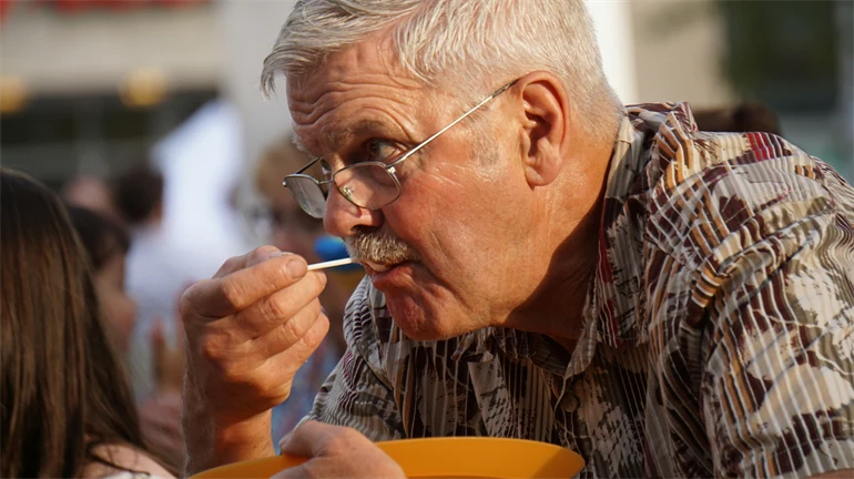 Äldre man som äter, utomhusmiljö.