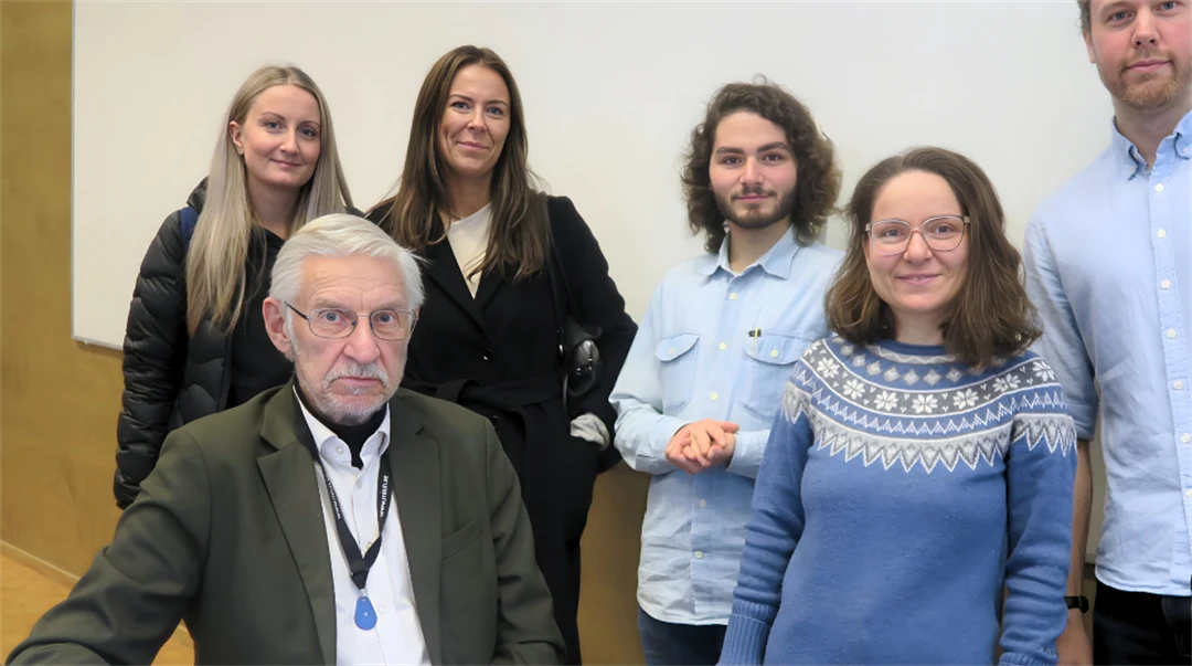 Manlig lärare i ett klassrum omgiven av fem studenter