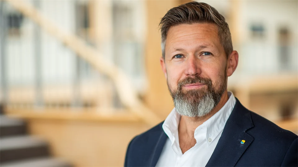 En man med skägg som har en vit skjorta och marinblå kavaj