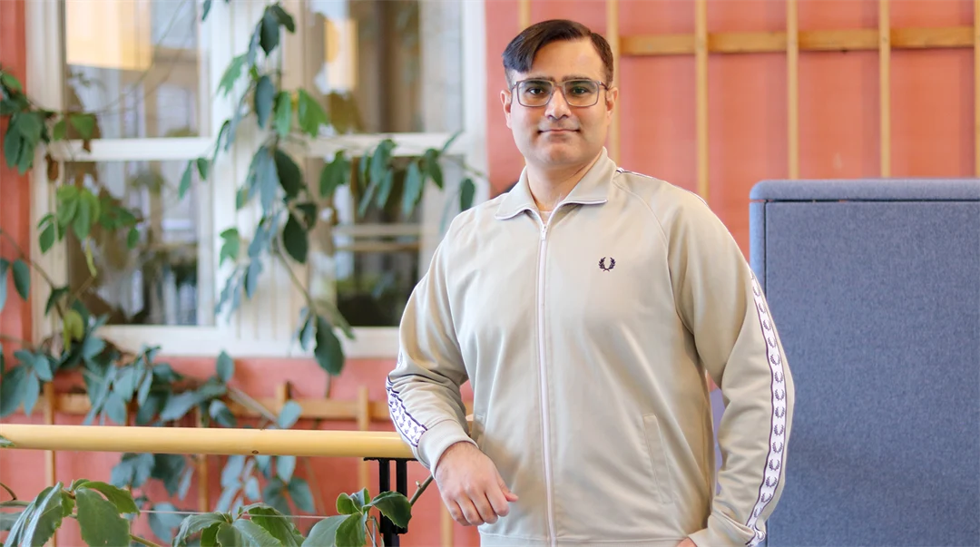 En man med glasögon och ljus tröja ler mot kameran.