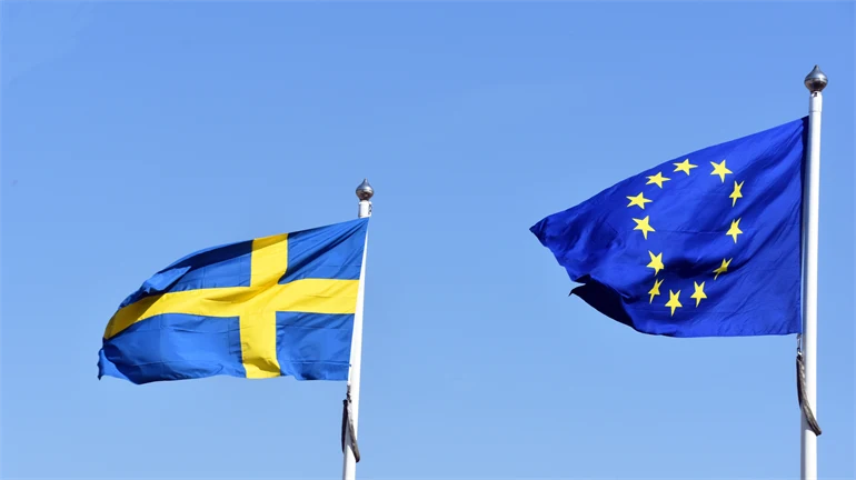 Svenska flaggan och EU flaggan mot blå himmel