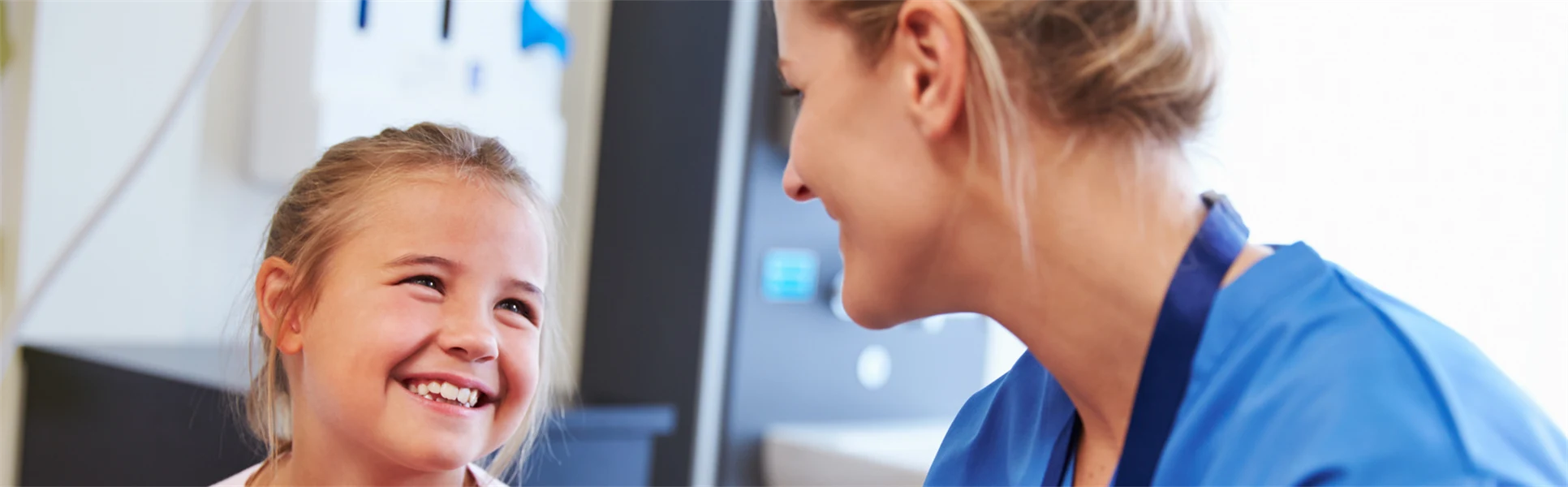 girl being reassured by nurse in hospital room.