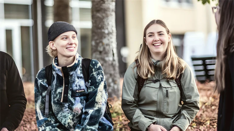 Fyra studenter sitter utomhus på campus i Östersund, de ser glada ut glada och pratar med varandra 