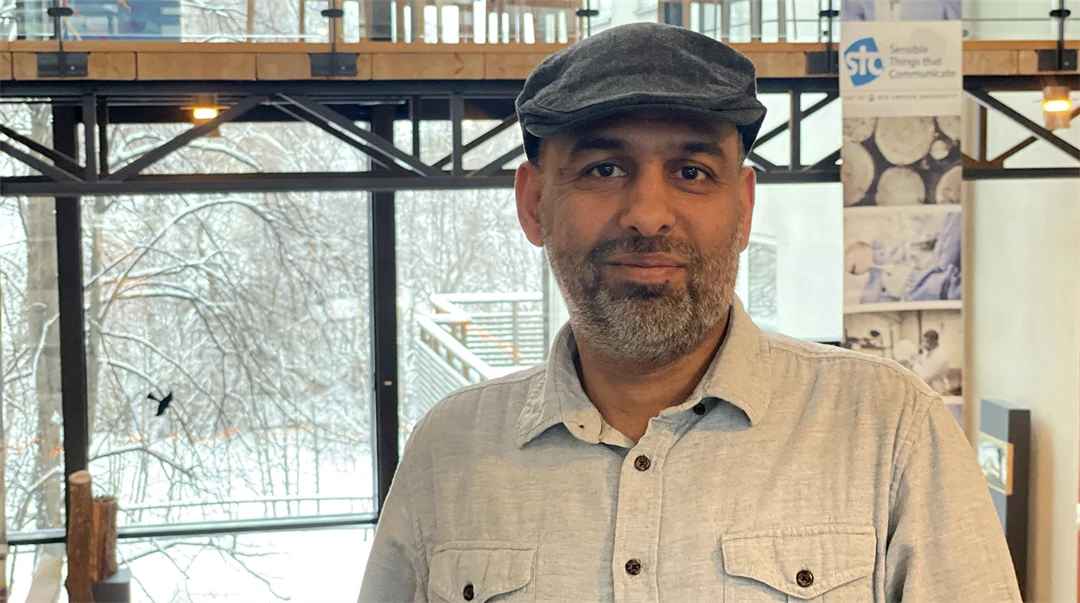 Man i grå keps och ljus skjorta poserar framför kameran.