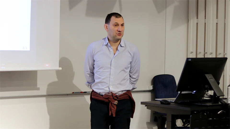 En mörkhårig man i ljus skjorta står framför en whiteboard tavla