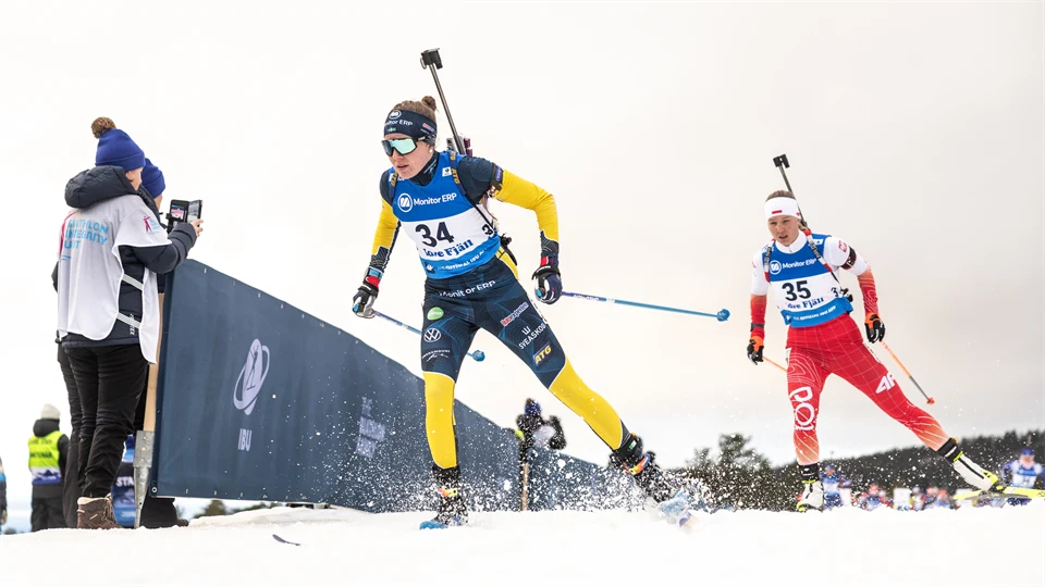 Skidskytt i svensk landslagsdress skidar mot kameran