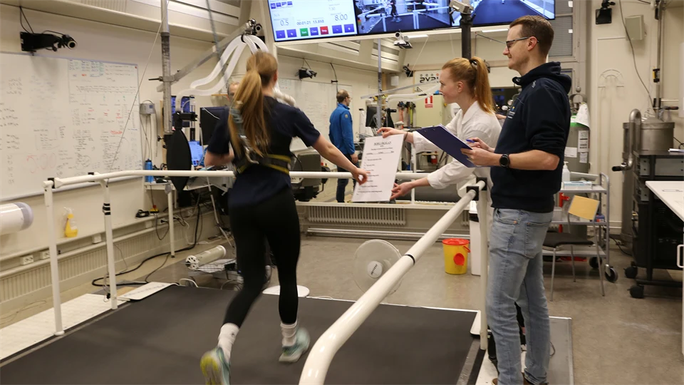 Lab environment with a runner on a treadmill and researchers next to it.