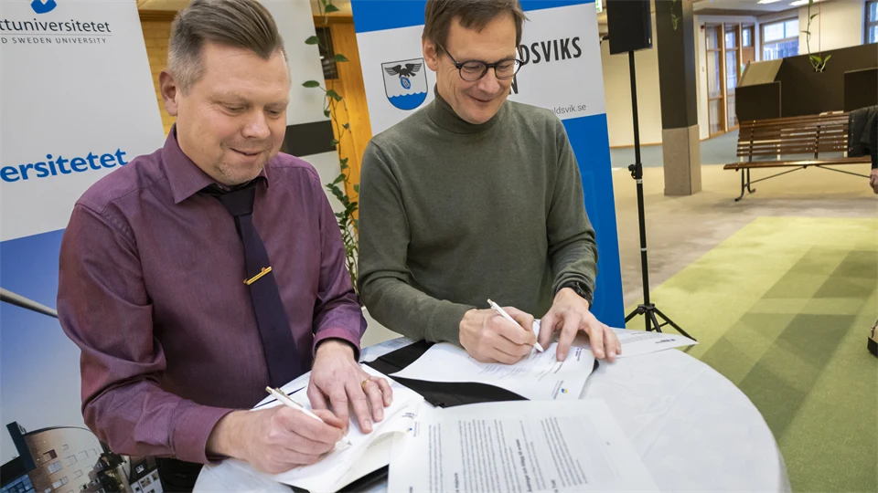 Rektor och kommunchefen i Örnsköldsviks kommun signerar varsitt dokument 
