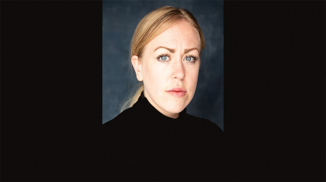 Ett porträttfoto av en blond kvinna mot svart bakgrund