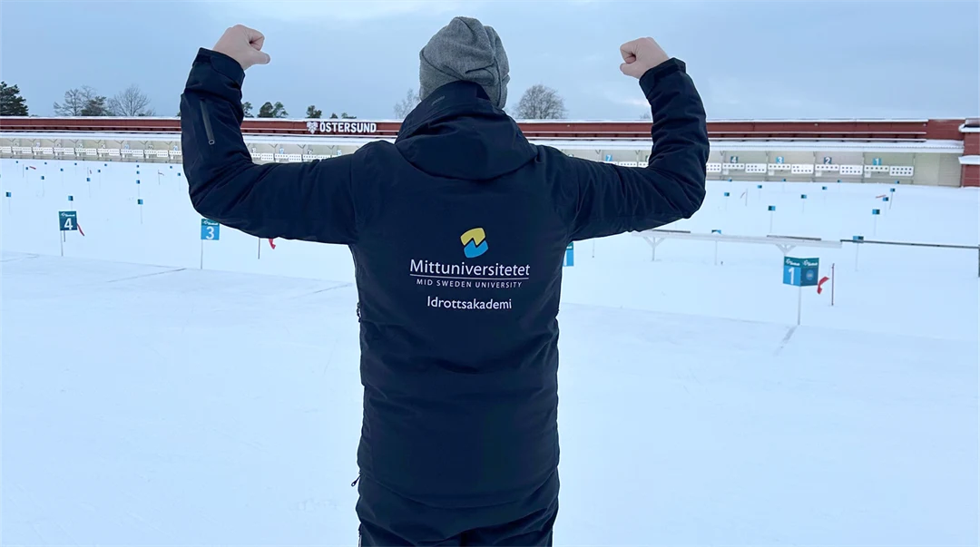 Man visar texten på ryggen av sin jacka med en "jag är stark" pose.