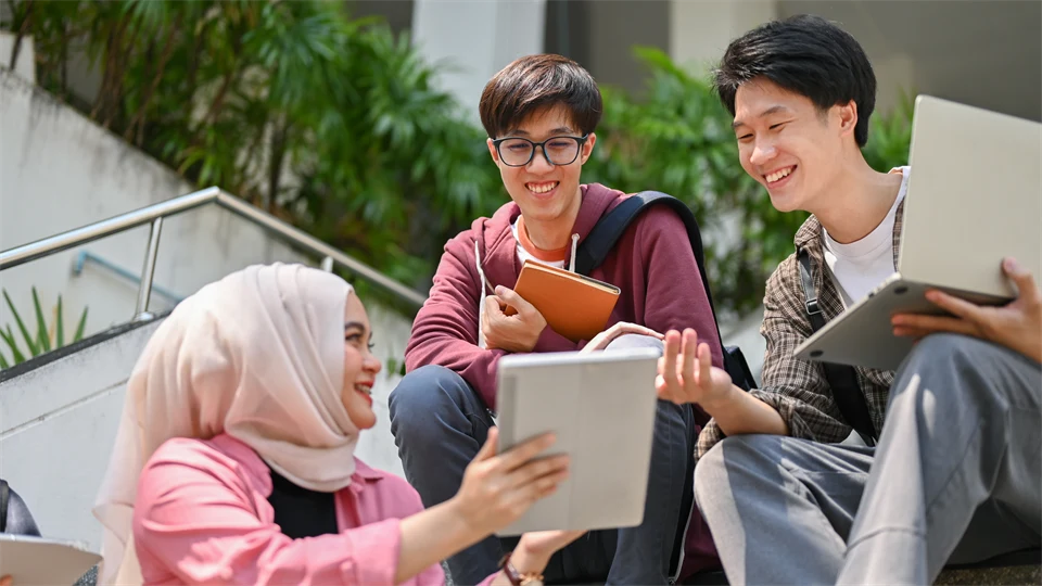 Tre studenter som sitter i en trapp på ett universitet och pratar.