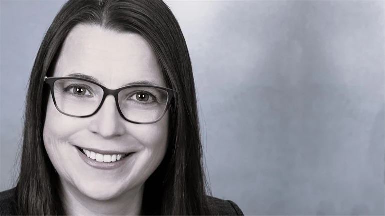 A woman with brown hair and glasses smiles