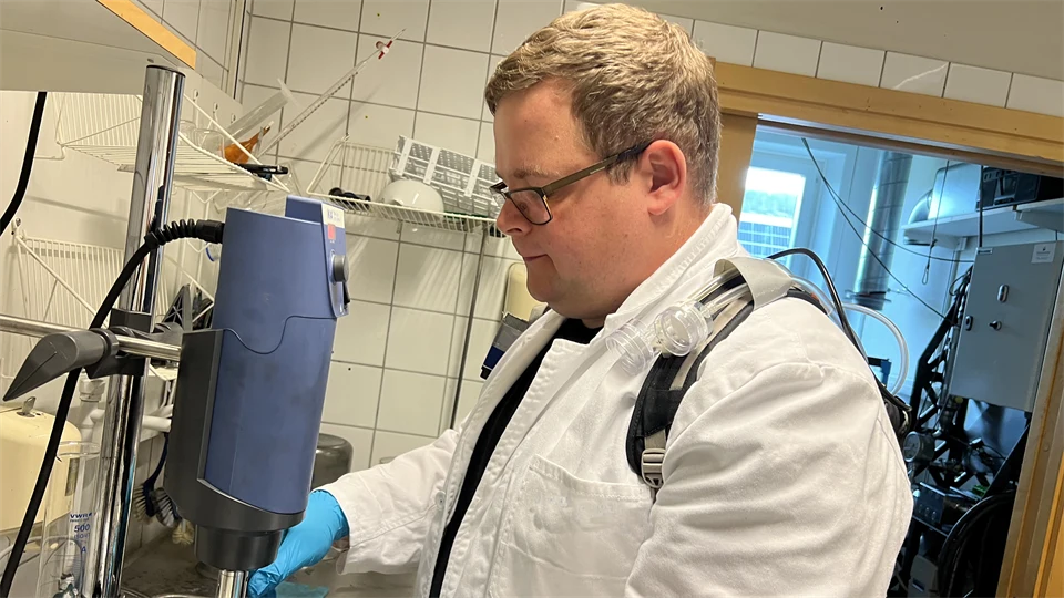 En man i vit laboratorierock arbetar i ett laboratorium.