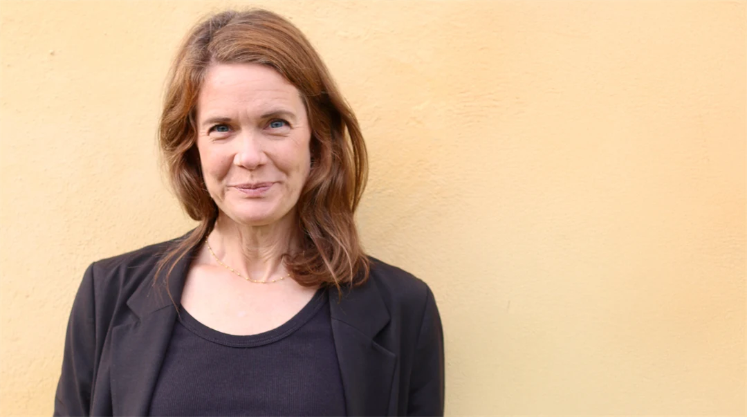 Portrait of a woman standing in front of a yellow wall.