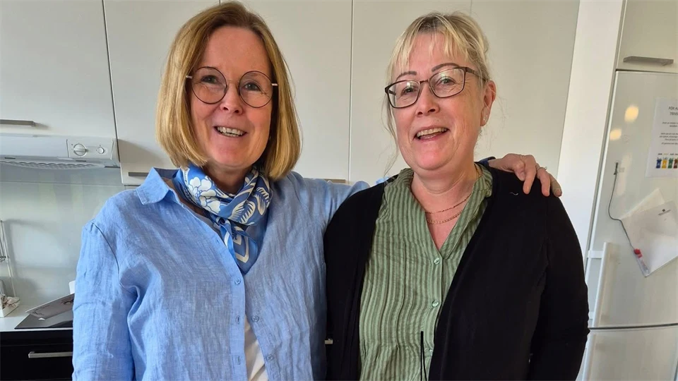 Två kvinnor ler in i kameran