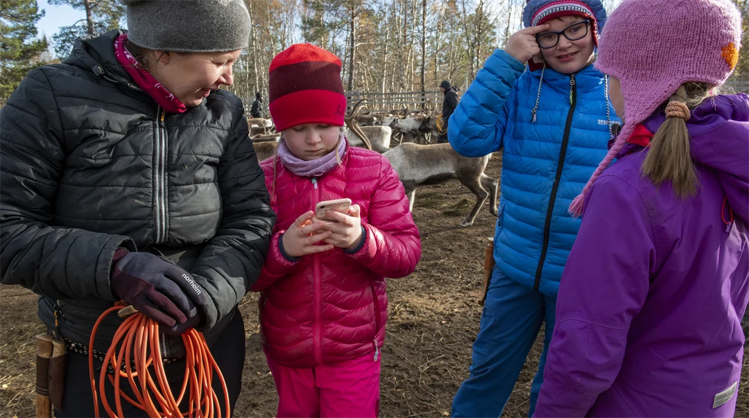 En flicka visar något på sin mobil för en kvinna.