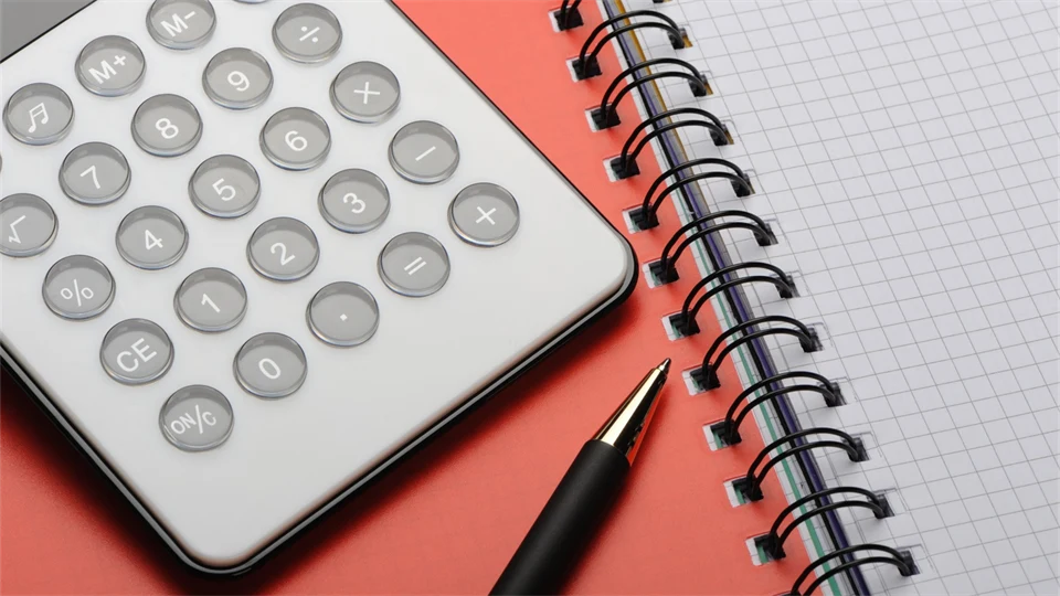  A calculator and a pen lie on a notebook.