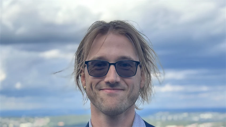 Porträttfoto av en man med blå kavaj och mörka glasögon