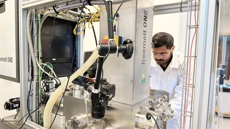 A man in a white coat working with a machine in a lab environment
