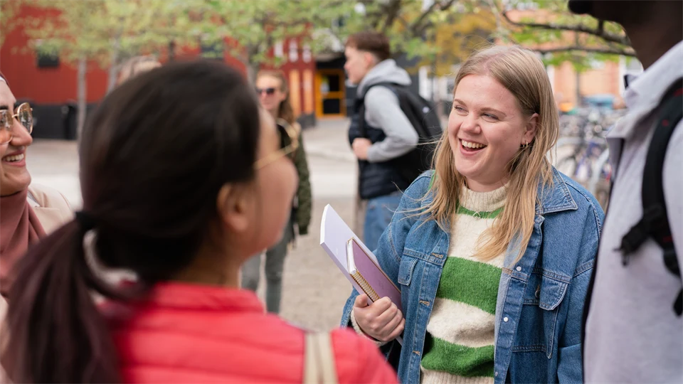 En grupp studenter som står och pratar med varandra utanför campus. 