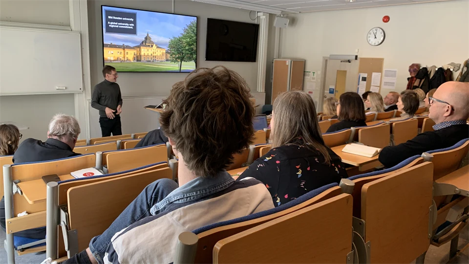 A lecturer in a classroom with an audience.