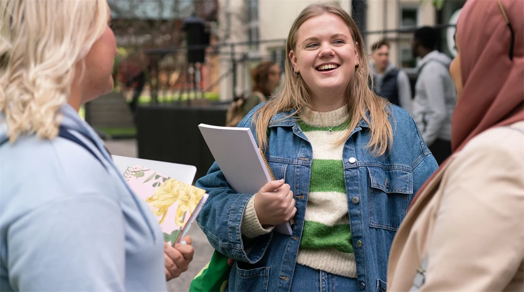  En grupp studenter som står och pratar med varandra utanför campus. 