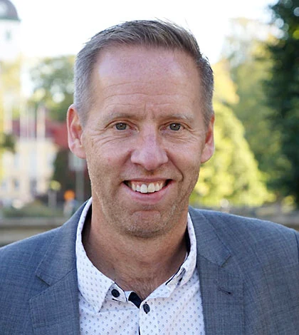 Man i grå kavaj utomhus.