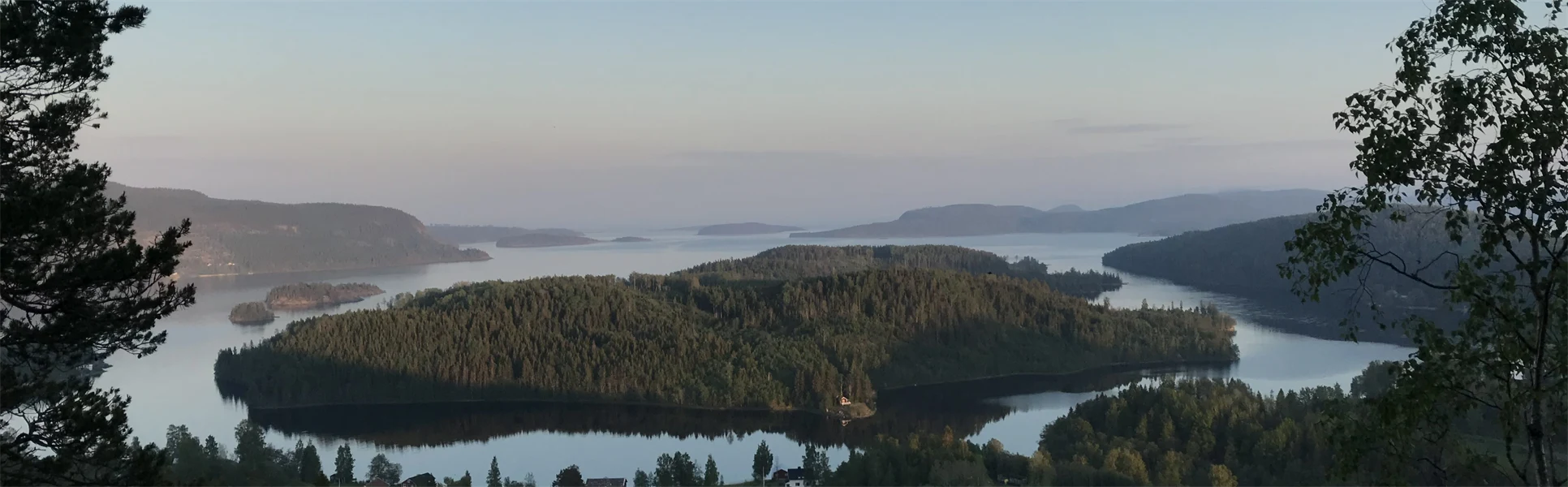 Utsikt över skogsklädda öar i stilla vatten.