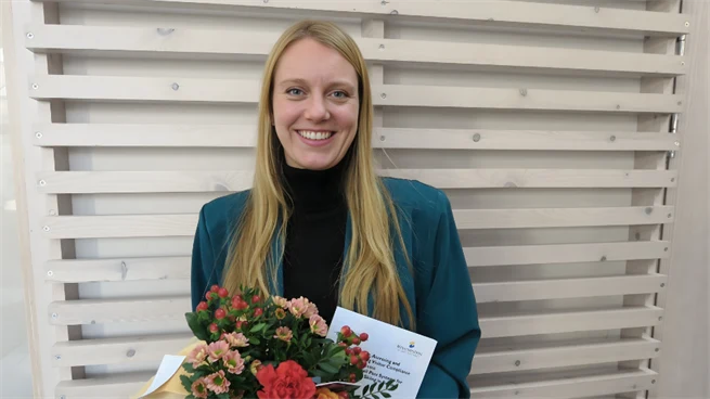 Kvinnlig forskare håller blombukett och doktorsavhandling