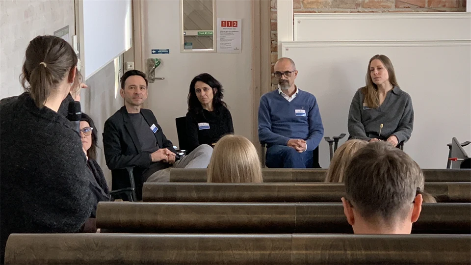 En panel med fyra personer sitter längst fram i en föreläsningssal med publik.