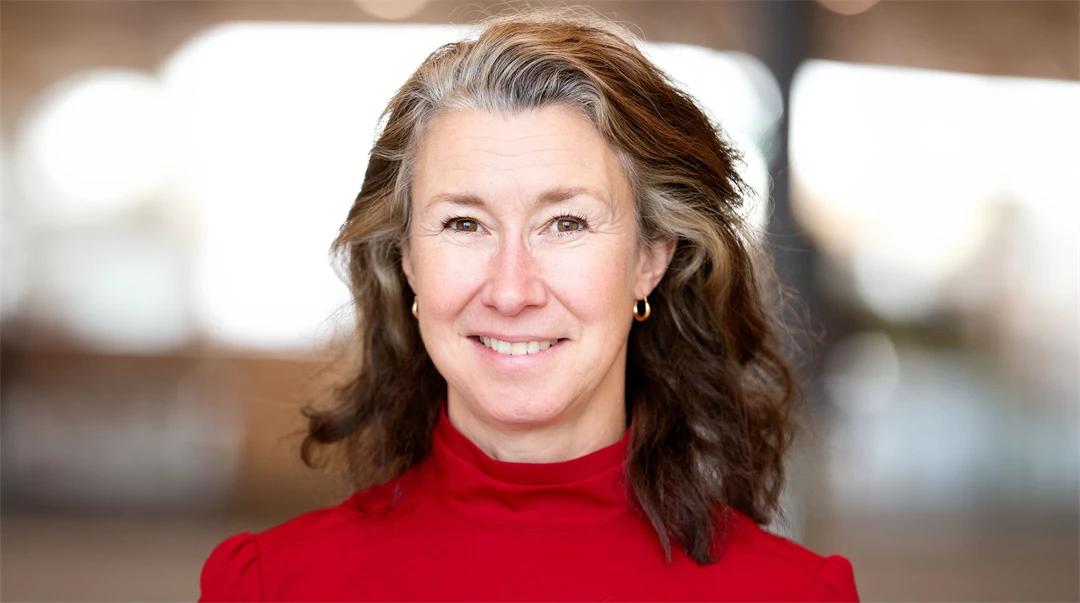 Kvinna med grånande hår och klarröd tröja.