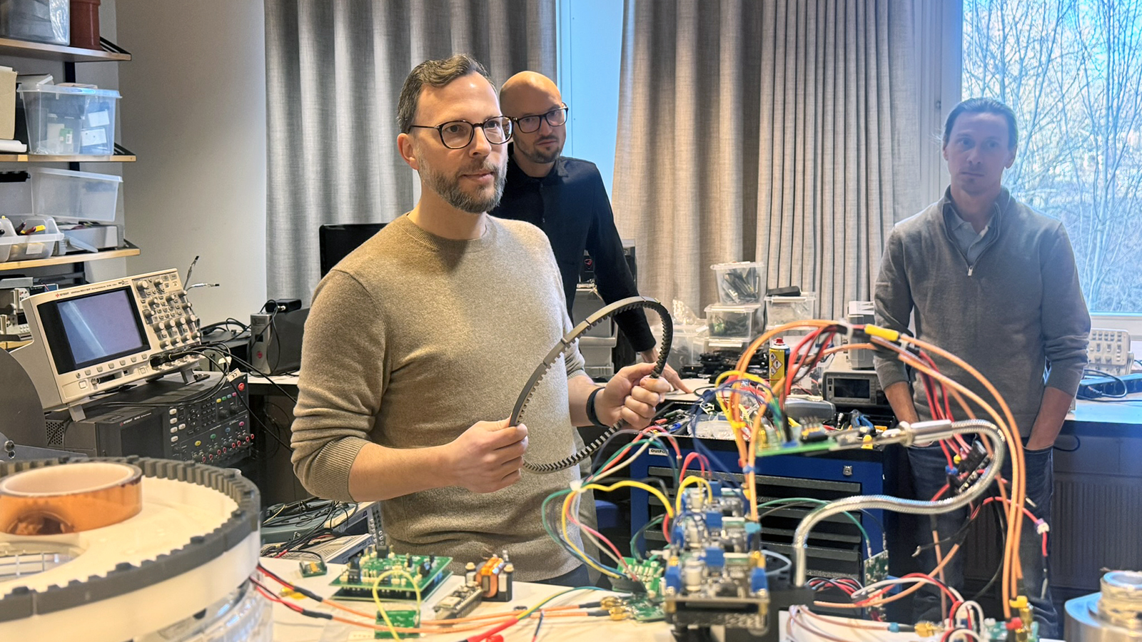 A man stands behind a lot of wires and he holds a round object