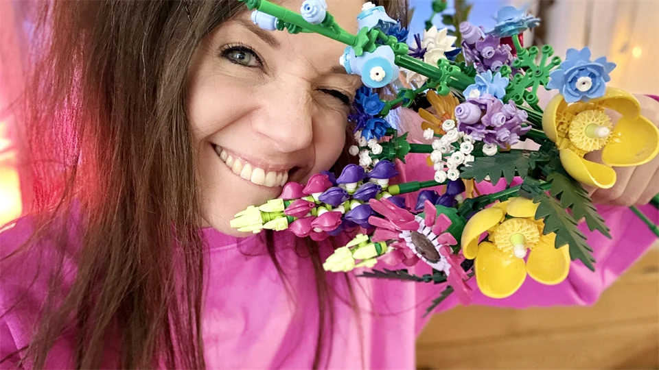 Bild på Samverkets community manager Sandra Olofsson i rosa tröja och en bukett legoblommor