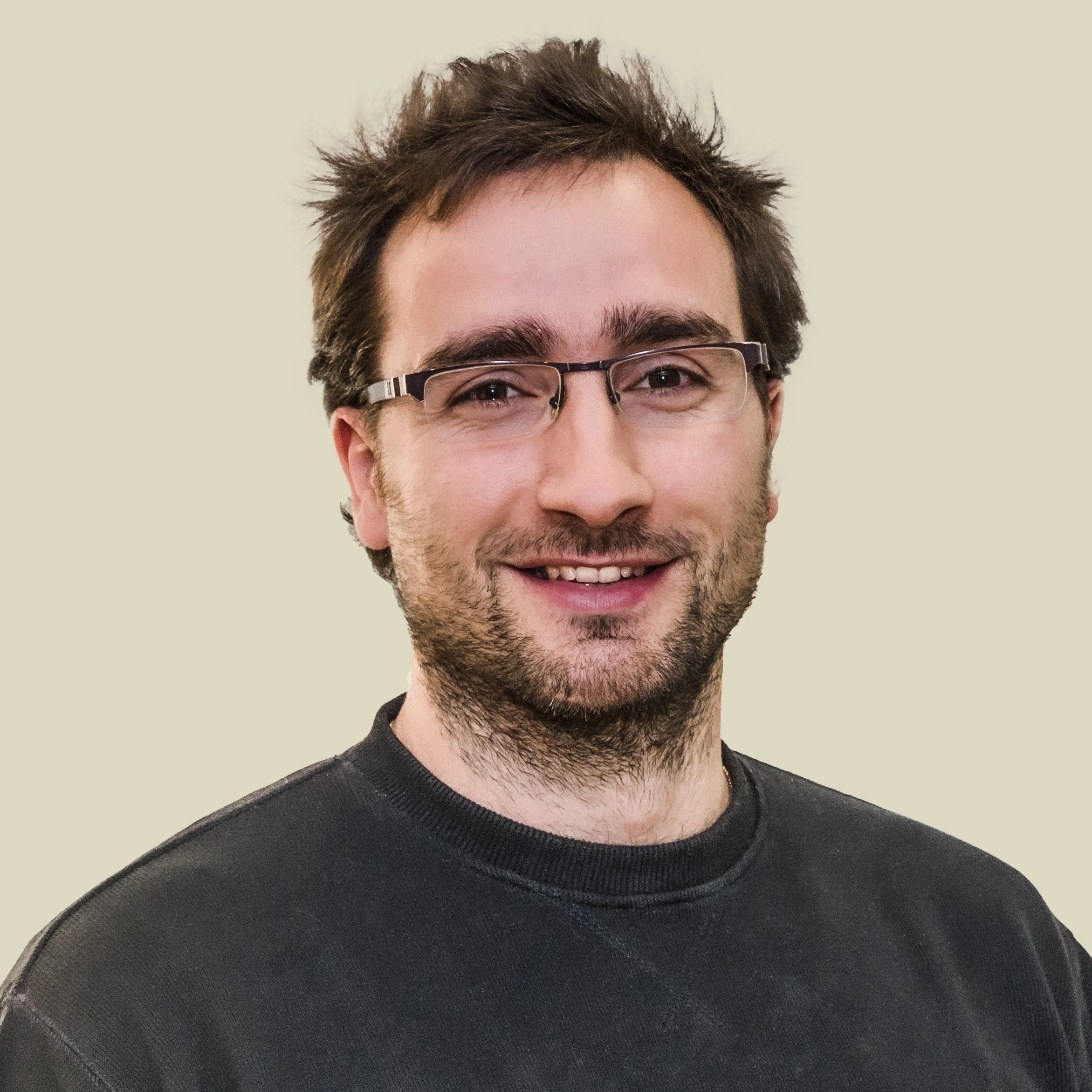  A smiling man with dark hair and glasses.