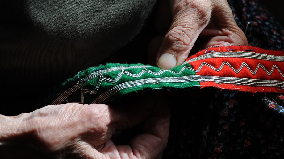 Martha Elise Jåma syr med tenntråd på ett sydsamiskt bälte. 