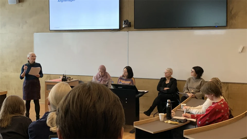 Five people on a panel in front of an audience in a seminar hall.