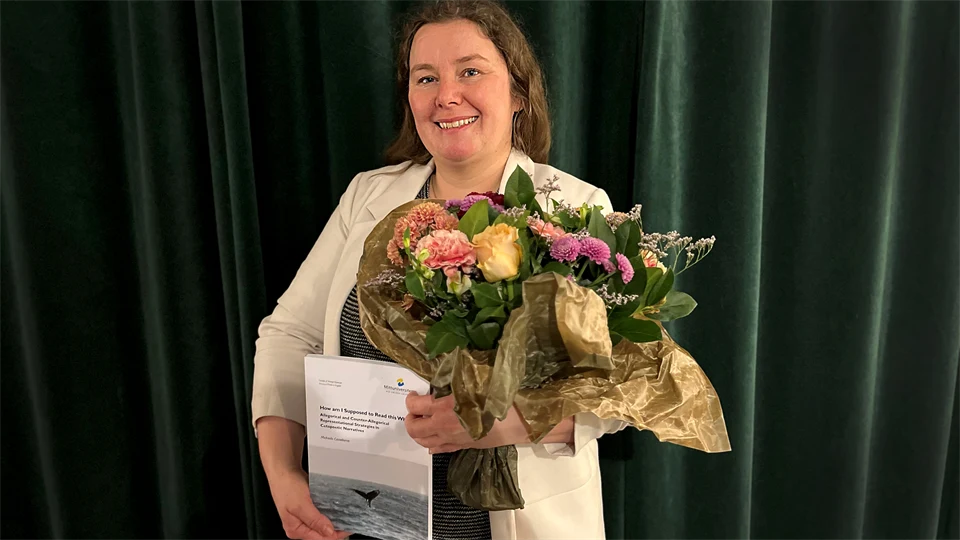 Kvinna håller en blombukett och en avhandling.