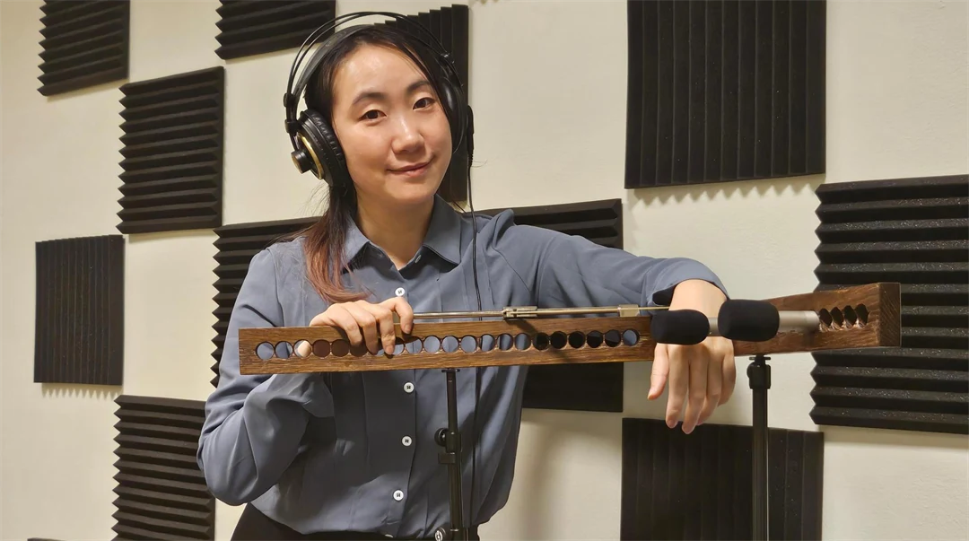 Woman in a blue shirt, with headphones on her head, leans over an array of microphones.