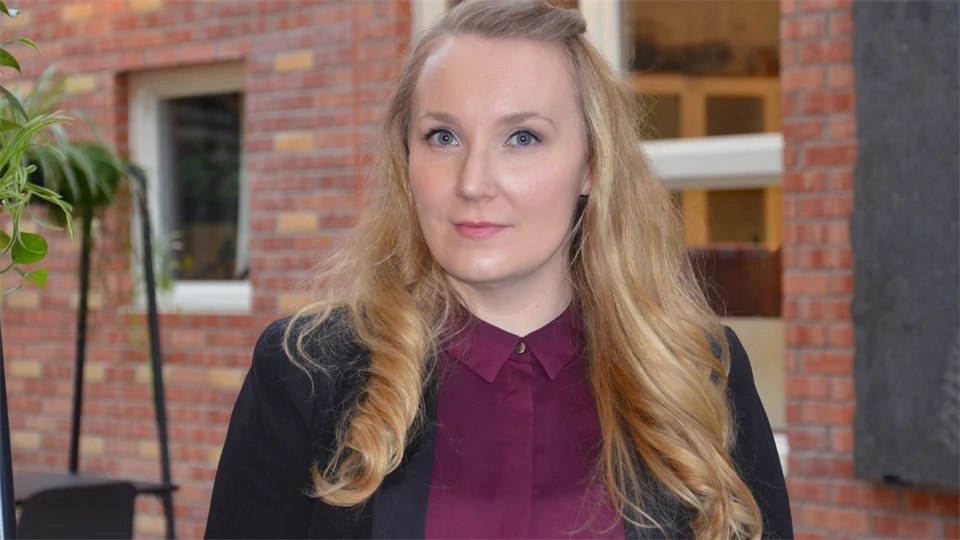 Kvinna med långt hår, vinröd blus och svart kavaj
