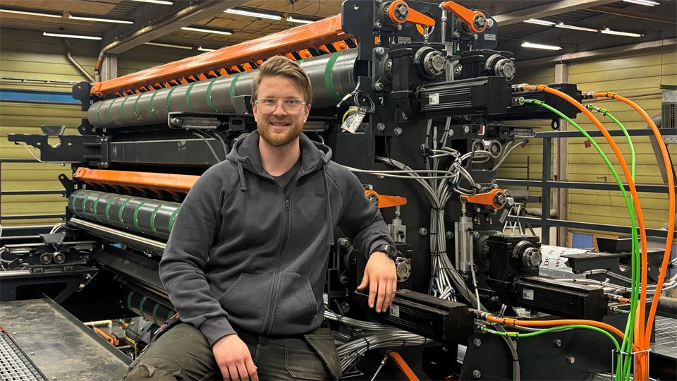 En man sitter framför en industrimaskin.