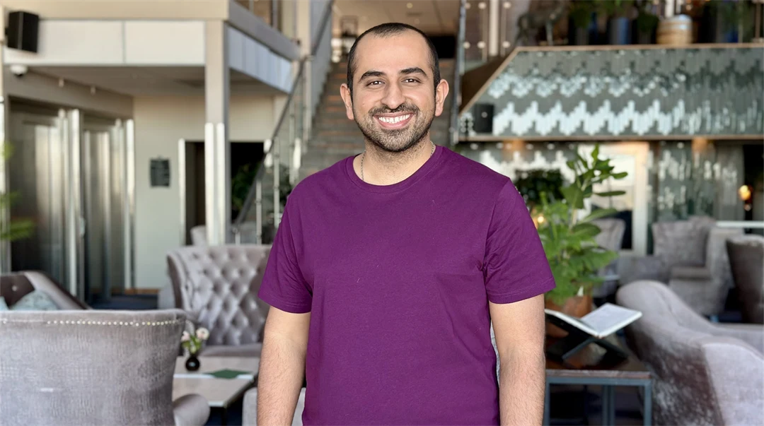 Smiling man with a buzz cut wearing a purple t-shirt.