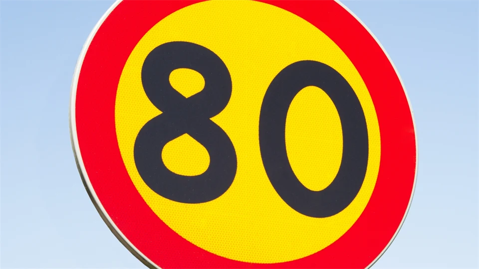 Hastighetsskylt - 80 i svart text mot gul bakgrund omgivet av röd cirkel