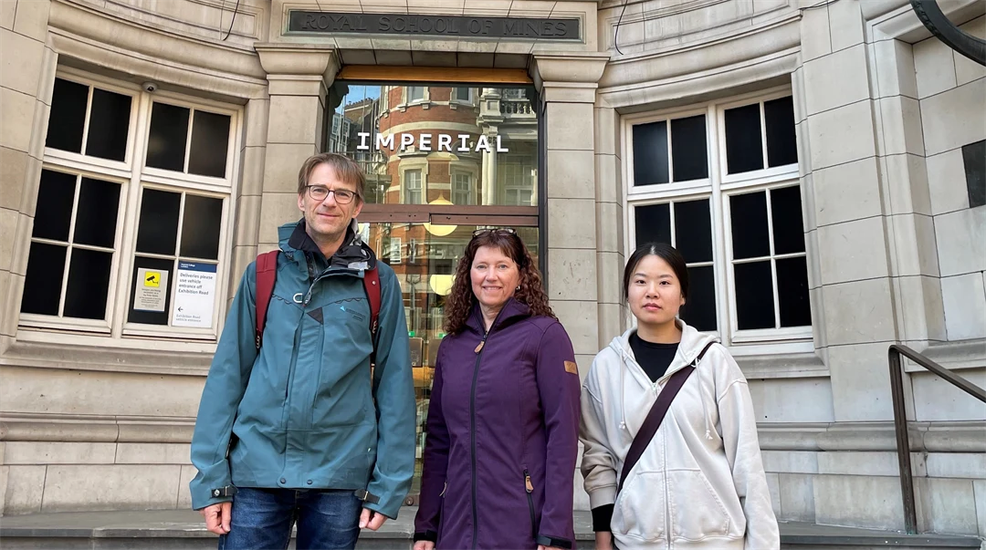  A man and two women are standing in front of a building.