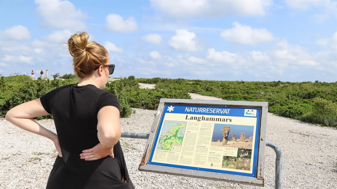 Turist står och kollar på karta över Langhammars  naturreservat