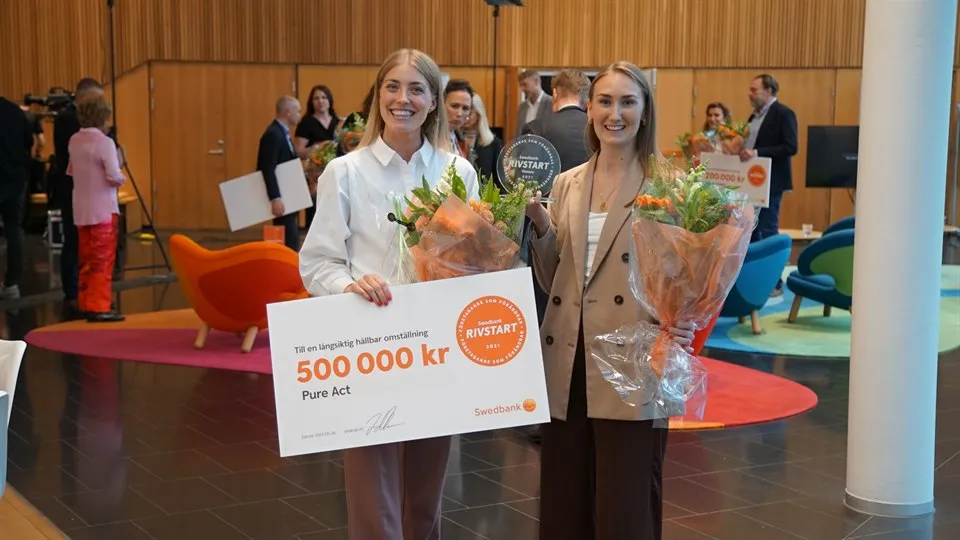 Vinnare av tävlingen Swedbank rivstart, bild på två tjejer som håller i en skylt med prispengen en halv miljon 