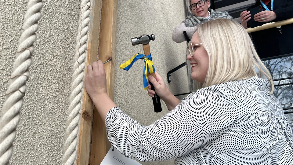 En kvinna som hamrar in en spik i en vägg