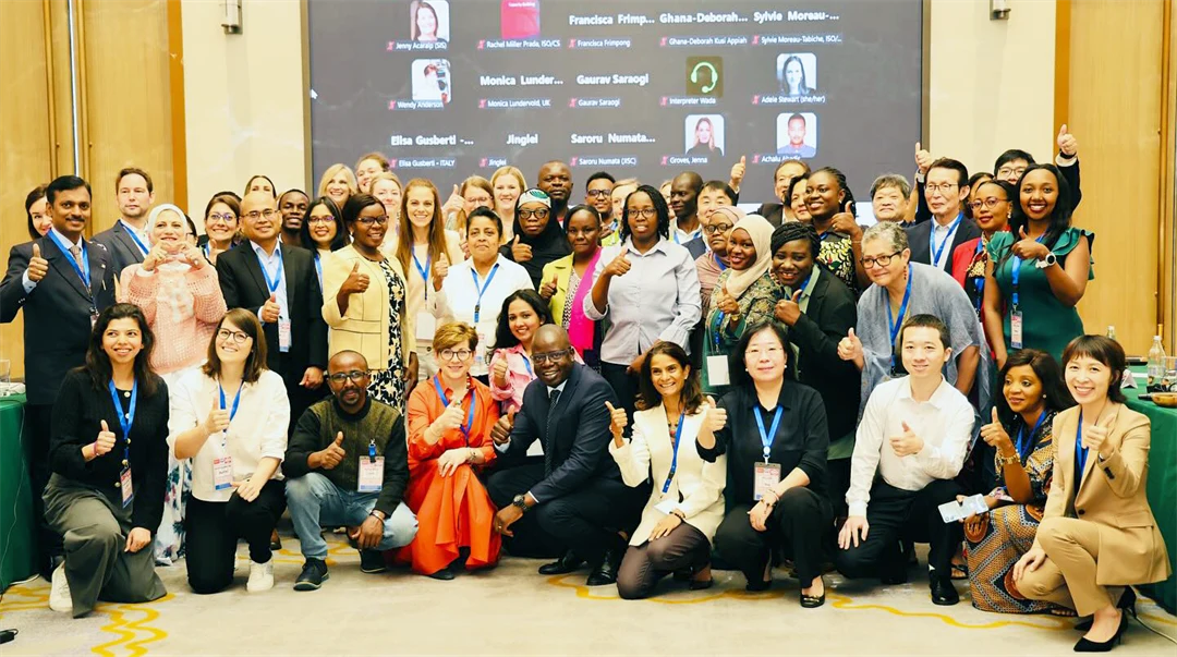 En stor samling människor med olika etnicitet ler mot kameran. Flera gör "tummen upp". 