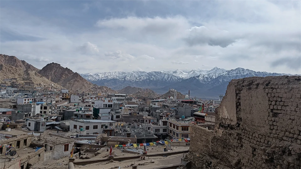 Slitna stadskvarter i ett kargt landskap. I bakgrunden höga berg med snö på topparna.